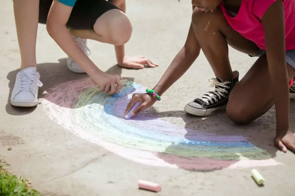 Two teenagers drawing a rainbow together, exemplifying a constructive conflict resolution activity for teens