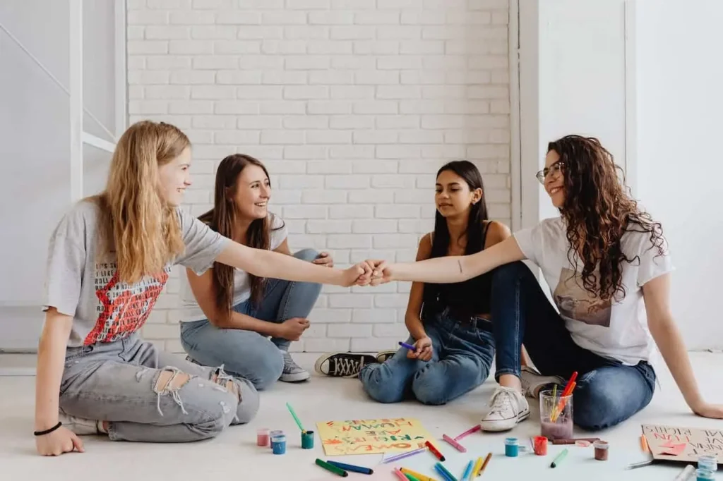 Photo of teens happily painting together, highlighting the importance of conflict resolution activities for teens