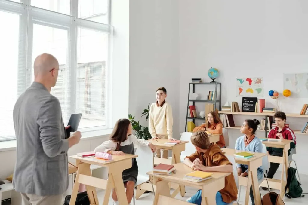 a teen boy standing in the class asking questions confidently showing strong communication skills