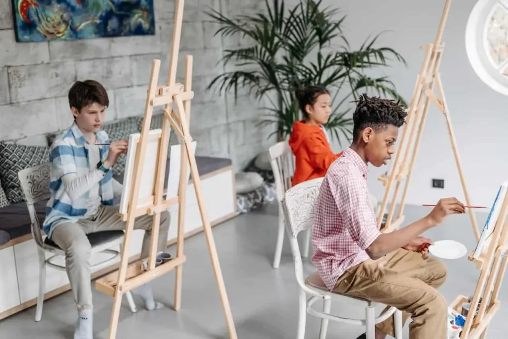 Three teenagers participating in art projects and drawing their thoughts on the paper as communication activities for teens