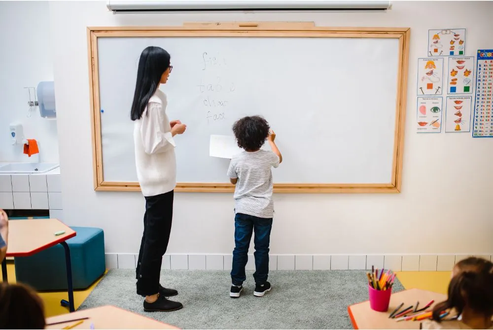 A teacher standing with her student before the white board and performing question-quest activity during morning meeting