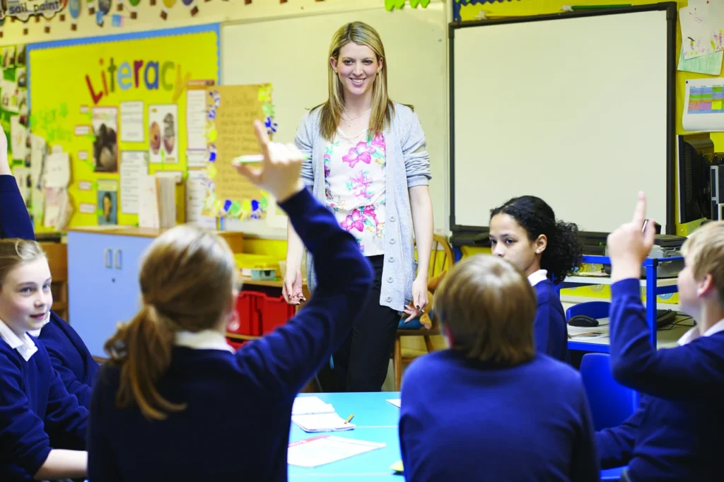 In the morning meeting, the teacher standing in front of the students, and they are greeting each other enthusiastically with smiling faces.