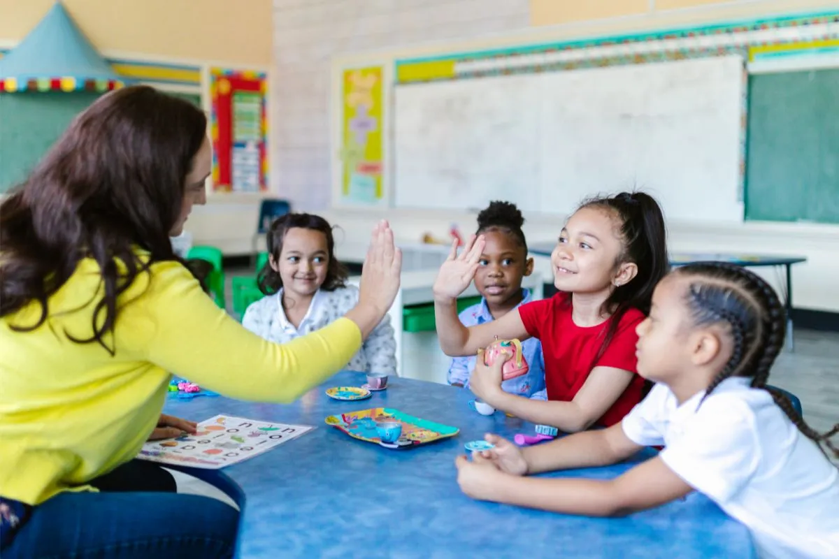 A teacher with her students extending their hands for a high-five greeting in morning meeting