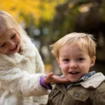 Two small kids; brother and sister are smiling and looking happy after resolving conflict